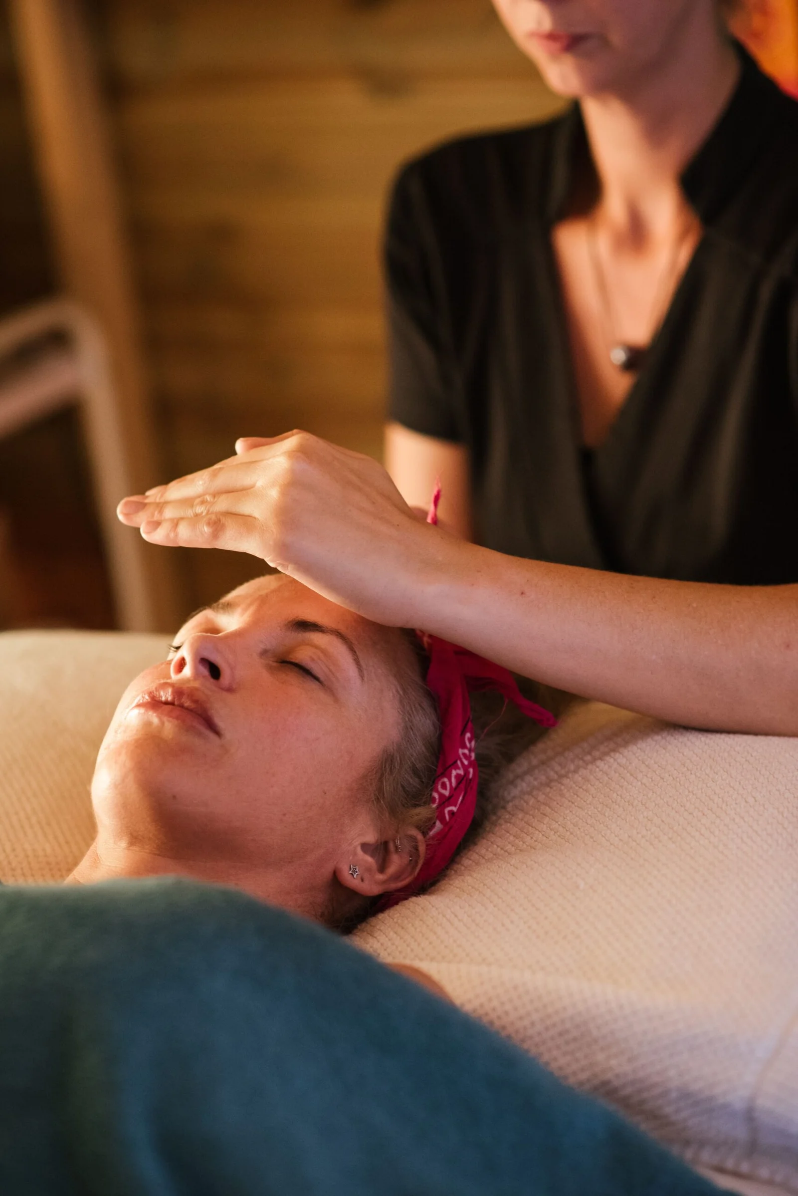 Imposition des mains sur le front d’une personne allongée pendant un soin énergétique Reiki à Comines